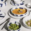 Piatti minimalisti in ceramica giapponese Yunoki ware, firmati Alessi, che uniscono eleganza e tradizione per una raffinata esperienza culinaria.
